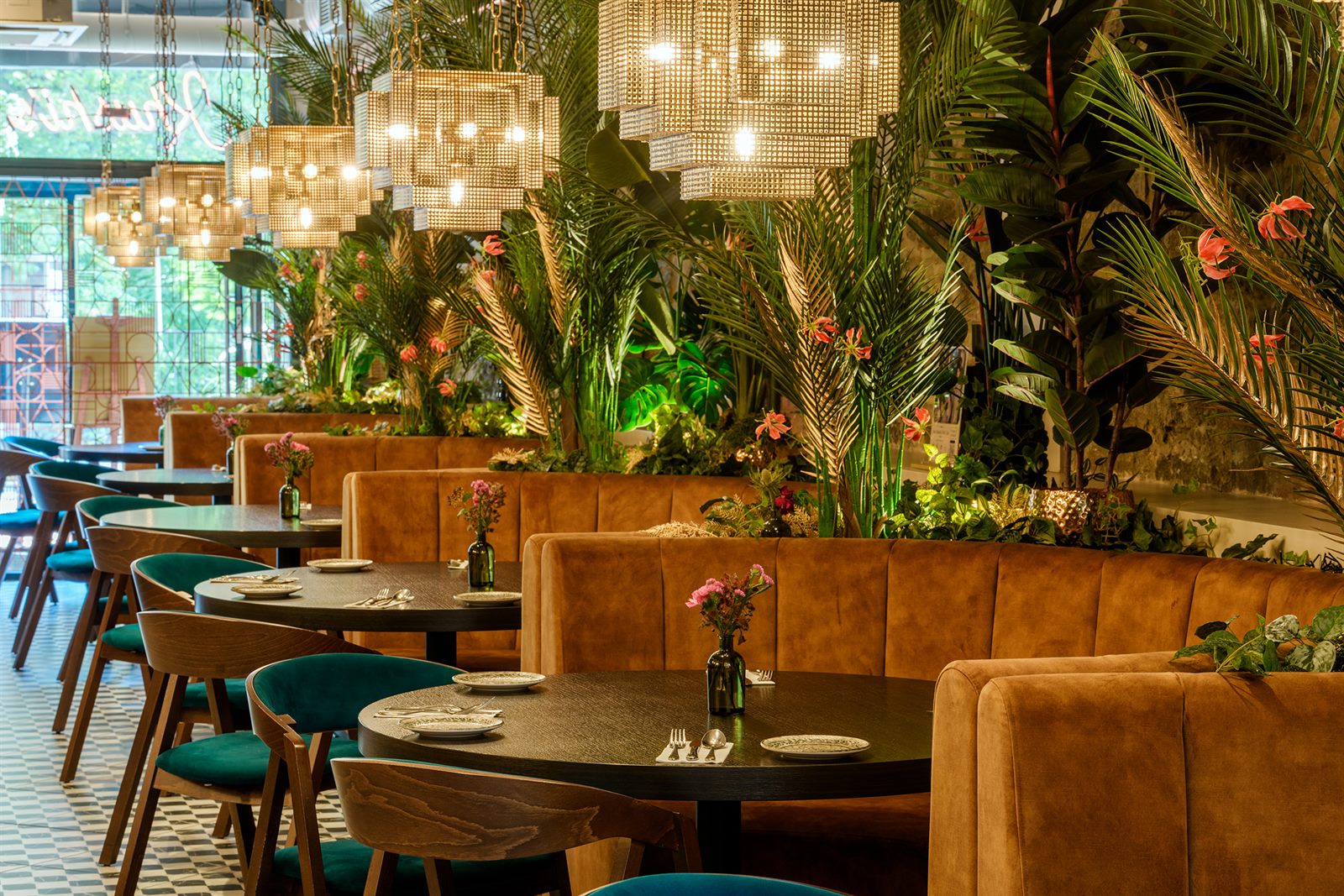 Khushi’s dining room, with velvet booths, lush greenery and glowing pendant lights